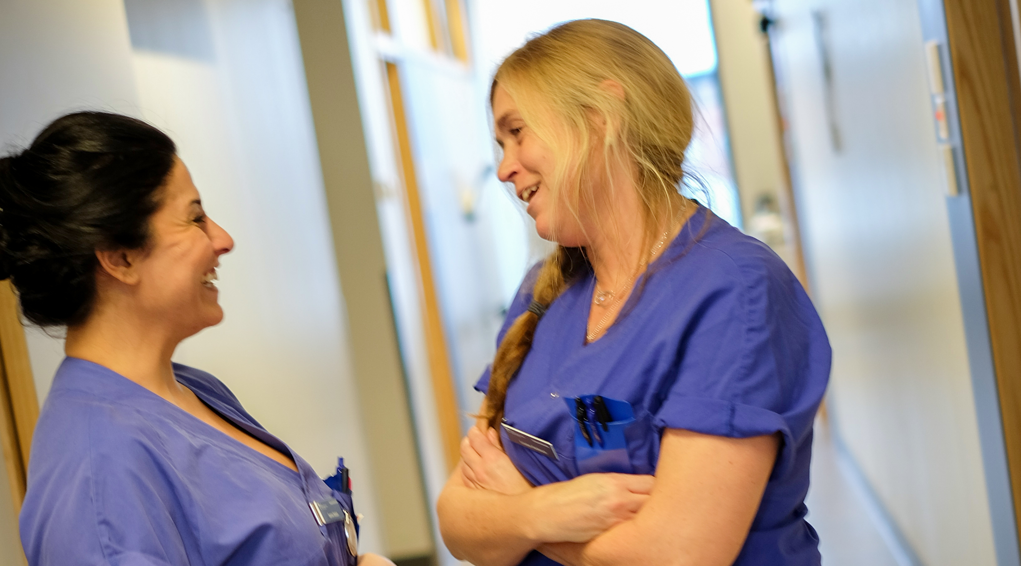 Två medarbetare står i en korridor och pratar med varandra.