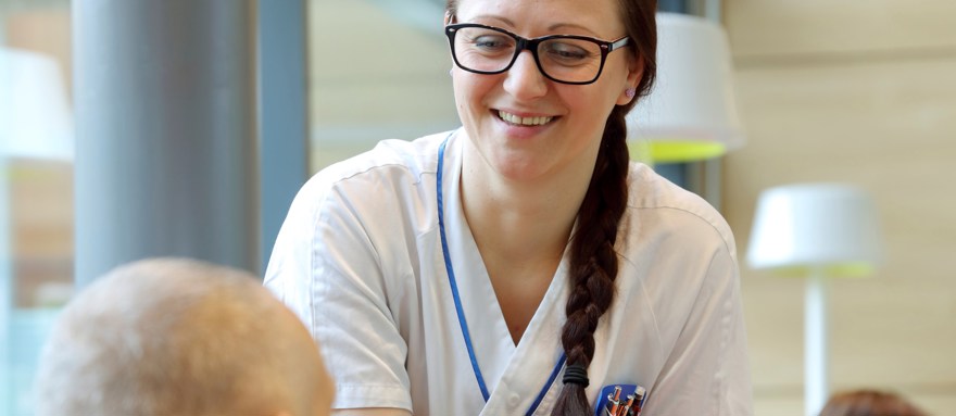 Vårdpersonal möter patient i väntrum.