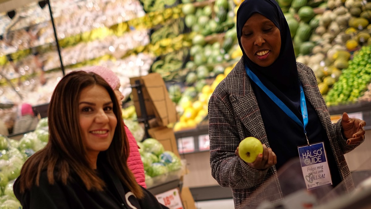 Två kvinnor vid fruktdisken i livsmedelsbutik