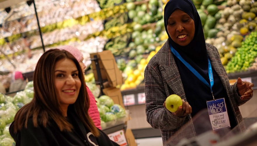 Två kvinnor vid fruktdisken i livsmedelsbutik
