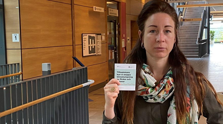 Kajsa tittar in i kameran med allvarlig blick. Hon håller en folder om könsstympning i handen.