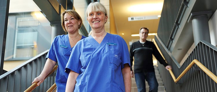 Vårdmedarbetare samt patient på väg ned för trappa.